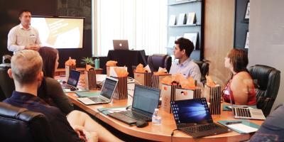 People sitting at boardroom table, watching a presentation.