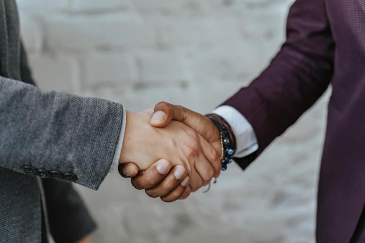 Photo of a handshake between two people wearing professional suits